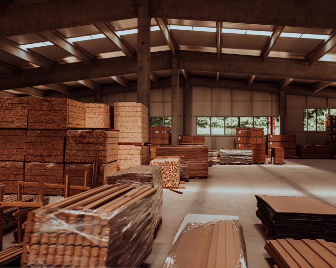 A vast warehouse in the forestry industry, showcasing a plethora of wooden products, including boards and various timber items neatly organized in storage.